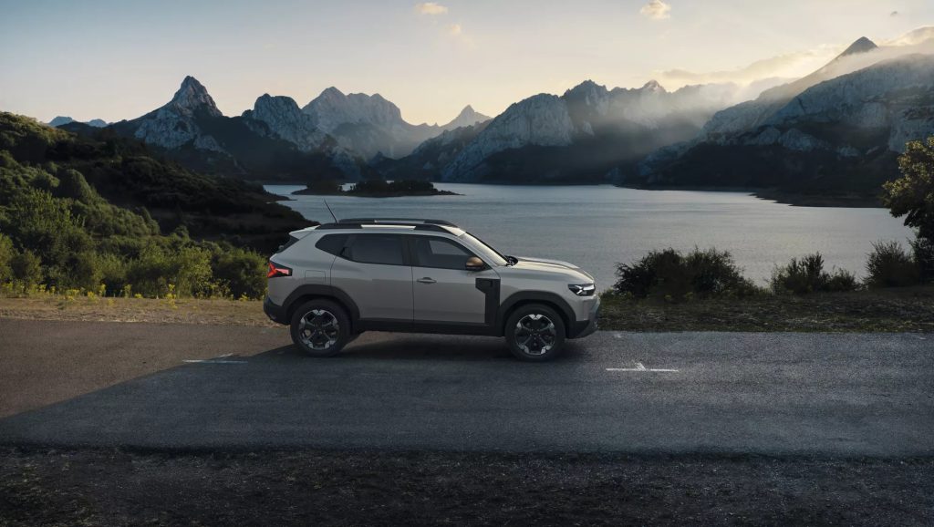 Bočni profil trećeg Dacia Dustera parkiranog pored jezera okruženog planinama