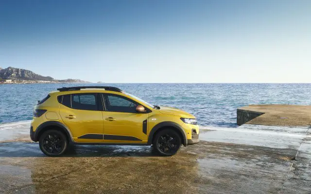 Dacia Sandero Stepway u žutoj boji, bočni profil, parkiran pored mora