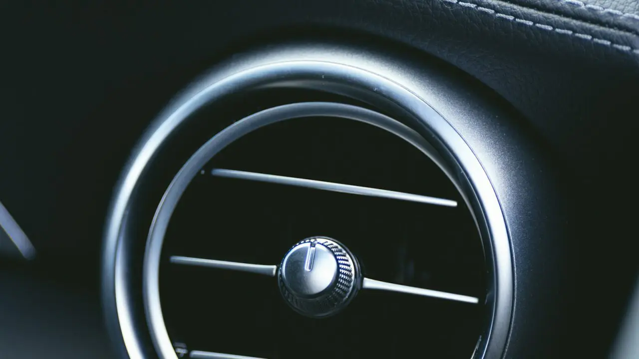 Krupni plan okruglog ventilacionog otvora klime na tabli automobila