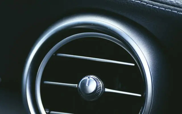 Krupni plan okruglog ventilacionog otvora klime na tabli automobila