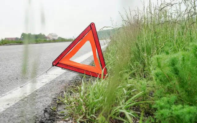 Trougao upozorenja postavljen pored puta, u travi na bankini