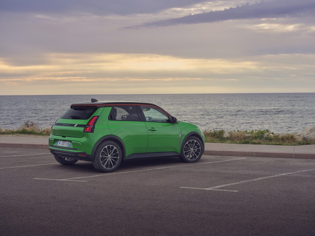 Renault 5 E-Tech electric u zelenoj boji fotografisan iz zadnjeg ugla na parkingu pored mora