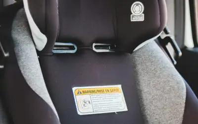 Detalj praznog dečijeg auto-sedišta u automobilu, sa kopčama pojasa i nalepnicom sa bezbednosnim uputstvom