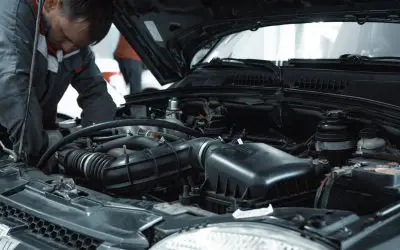 Mehaničar proverava motor polovnog automobila ispod podignute haube