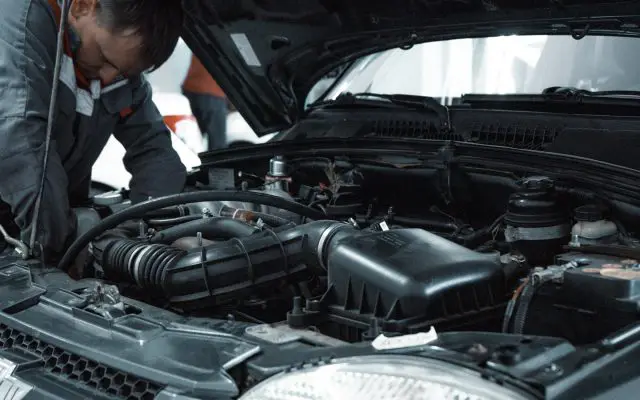 Mehaničar proverava motor polovnog automobila ispod podignute haube