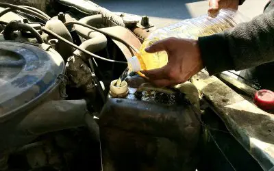 Sipanje motornog ulja u motor automobila sa plastične flaše, detalj sa radioničkog dvorišta
