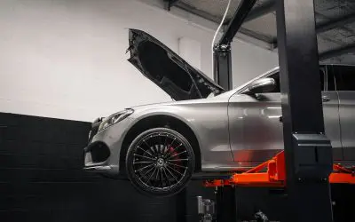 Automobil na hidrauličnoj dizalici u servisnoj radionici, otvorena haube, priprema za tehnički pregled