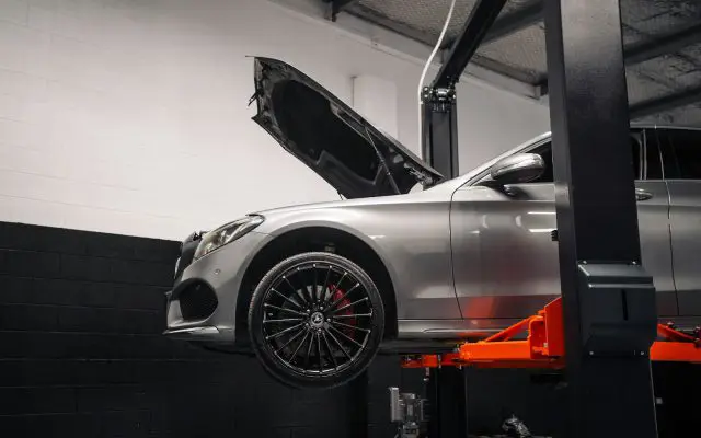 Automobil na hidrauličnoj dizalici u servisnoj radionici, otvorena haube, priprema za tehnički pregled