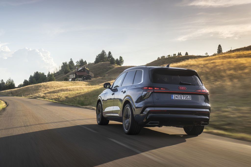 Audi Q7 model 2026 u vožnji, pogled od pozadi, dinamički snimak na seoskom putu