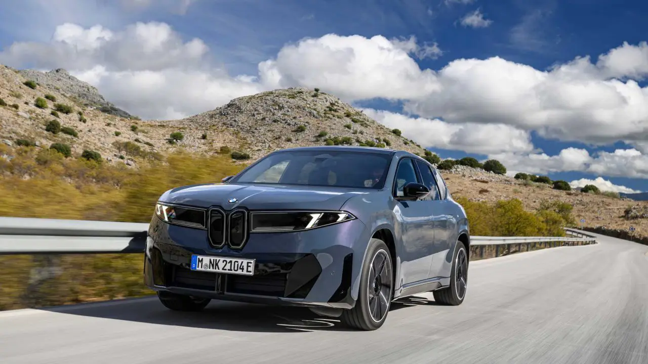 BMW iX3 50 xDrive u voznji na planinskom putu, pogled spreda i sa strane