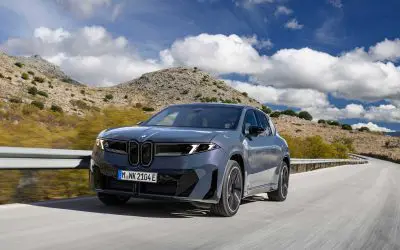BMW iX3 50 xDrive u voznji na planinskom putu, pogled spreda i sa strane