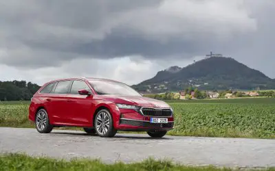 Škoda Octavia Hybrid 2026 u crvenoj boji, pogled spreda i sa strane na seoskom putu