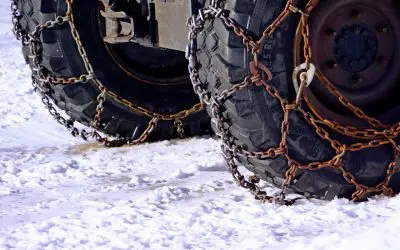 Dva točka sa montiranim lancima za sneg na zaleđenom putu