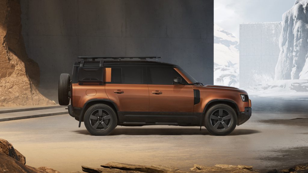 Land Rover Defender 110 u boji Namib Orange, bočni profil sa rezervnim točkom na zadnjim vratima