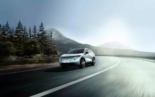 Nissan Ariya (fejslift 2026), prednji ugao u vožnji planinskim putem pored šume