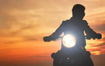 Silueta motocikliste u vožnji pri zalasku sunca, pogled sa prednjim farom